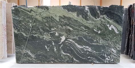 A Green Marble Counter Top Sitting In A Room Next To Other Tile And Stone Slabs