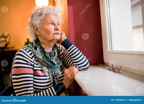 Sad Alone Senior Woman Looking Through Window At Home Stock Image