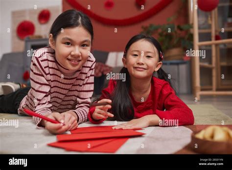 Retrato De Dos Jovencitas Chinas Que Yacen En El Suelo Creando Sobres