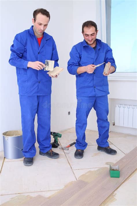 Two Workers Apply Glue To The Board For Floor With Stock Image Image