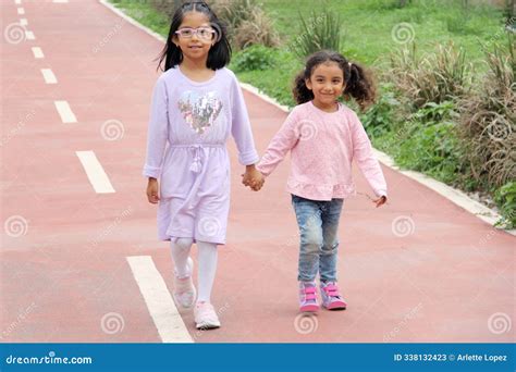 Latina And Year Old Girls Walk Holding Hands Like Sisters And Friends Spending Time Together