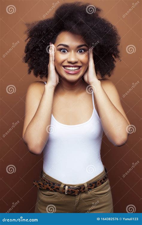 Pretty Young African American Woman With Curly Hair Posing Cheerful Gesturing On Brown