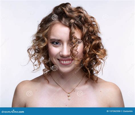 Portrait Of Young Smiling Woman With Curly Hair On Gray Background