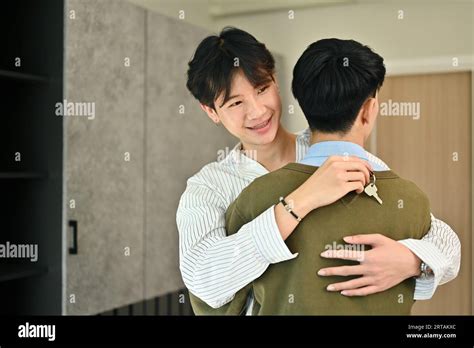 Happy Gay Man Couple Celebrating Moving Into New Home And Hugging Each Other LGBTQ Relocation
