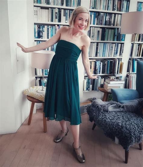 A Woman Standing In Front Of A Bookshelf With Her Arms Out To The Side