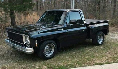 a black pickup truck parked in front of a wooded area with trees and ...