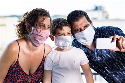 Familia feliz con máscaras protectoras tomando una selfie Foto Premium