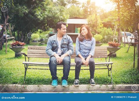 Young Smiling Couple Looking On Each Other While Sitting On Bench