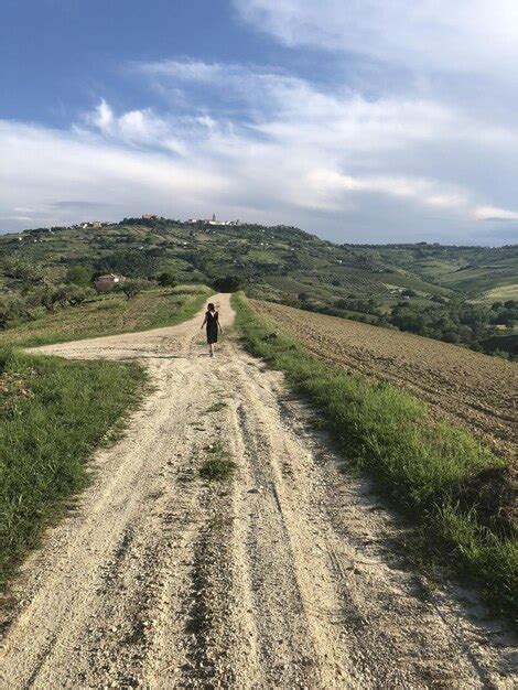 Vista Trasera De Una Mujer Caminando Por Un Camino De Tierra Contra El