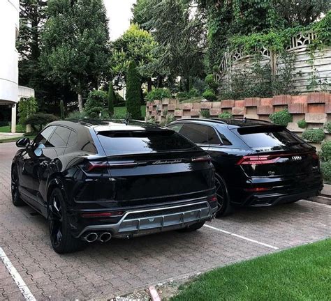 Two Black Cars Parked Next To Each Other In A Parking Lot