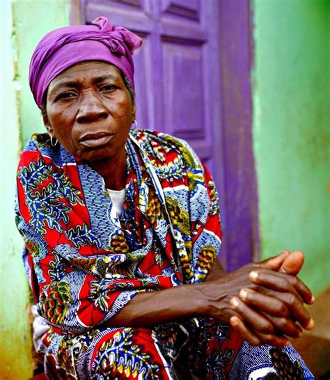 An Older Woman Sitting In Front Of A Purple Door