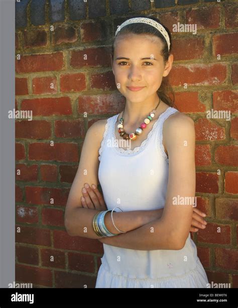 Pretty Girl Leans Against A Brick Wall In The Street Arms Folded