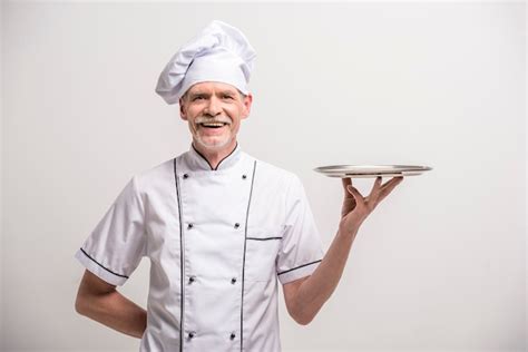 Premium Photo | Senior male chief cook in uniform holding tray.