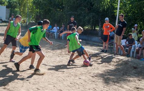 Soccer Boys Running For The Ball On A Sandy Field In A Summer Camp