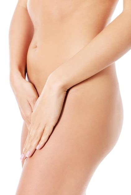 Sección media de una mujer desnuda que cubre la vagina contra un fondo blanco Foto Premium