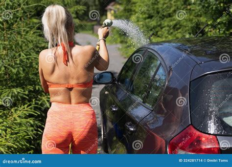A Fit Blonde Girl Washes Her Car Outdoors On A Summer Day Back View