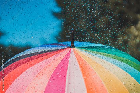 Bright colored rainbow umbrella in the rain Stock Photo | Adobe Stock