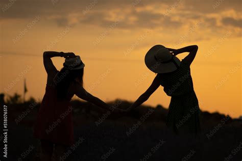 TWO GIRLS HOLDING HANDS IN A SUNSET Stock Photo | Adobe Stock