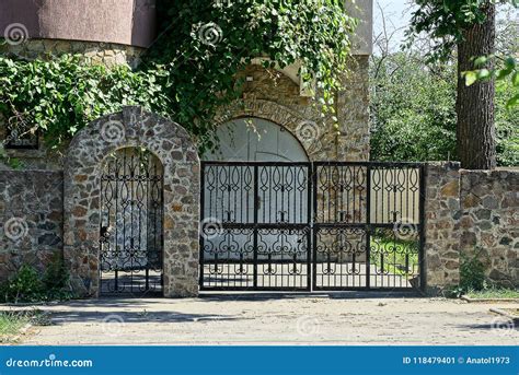 Black Iron Gates And Stone Fence In The Street Near The Asphalt Road