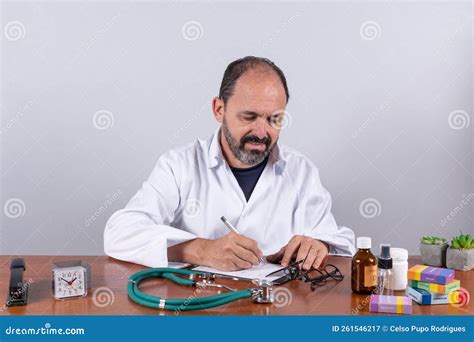 Portrait Of Senior Mature Doctor Pleasant Professional In White Coat Sitting At Table Stock