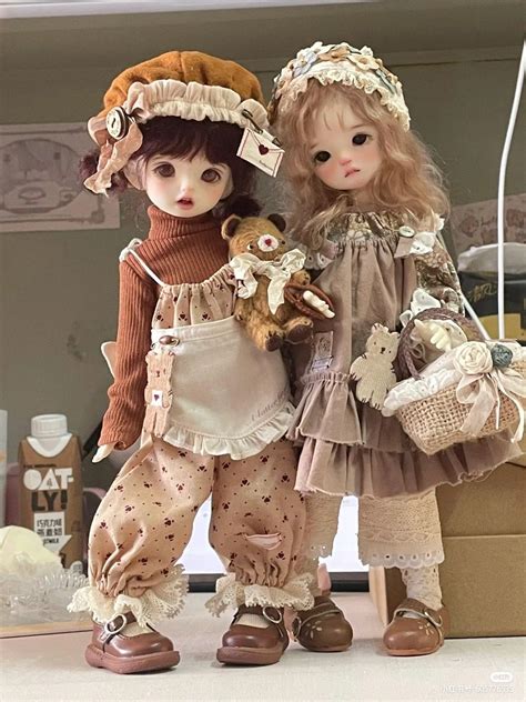 Two Dolls Standing Next To Each Other In Front Of A Box With Stuff On It