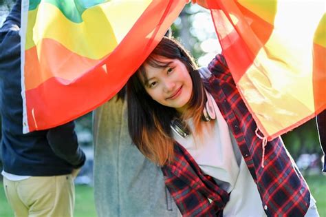 Bonita mujer asiática sosteniendo la bandera del arco iris lgbt con sus