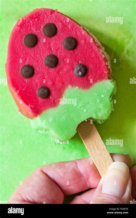 Holding Rowntrees Strawberry ice lolly set on green patterned background - strawberry and kiwi ...