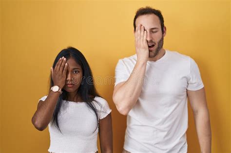 Interracial Couple Standing Over Yellow Background Yawning Tired