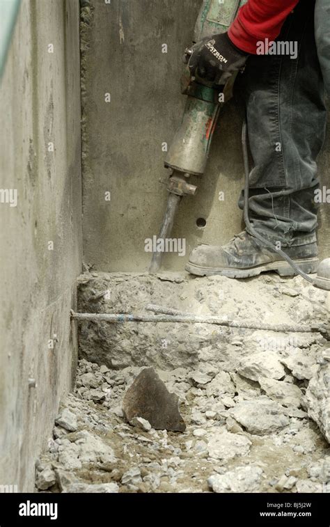 Worker breaking up concrete with an electric jack hammer Stock Photo ...