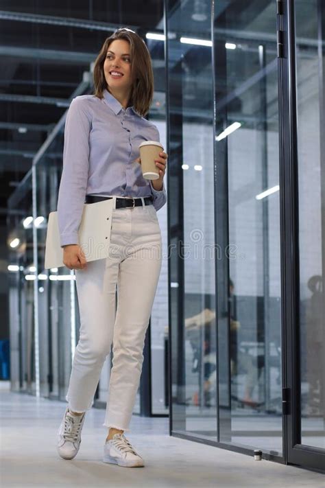 Businesswoman Walking Along The Office Corridor With Documents Stock