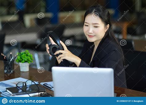 Businesswoman Holding Headphone While Looking At Laptop Screen Stock