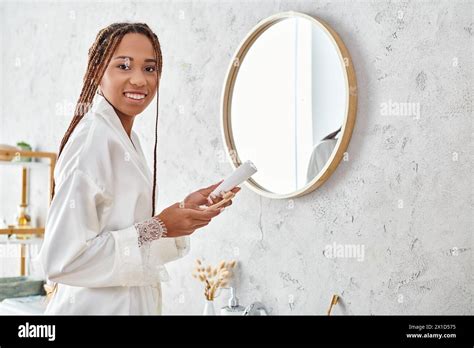 An African American Woman With Afro Braids In A Bathrobe Is Diligently