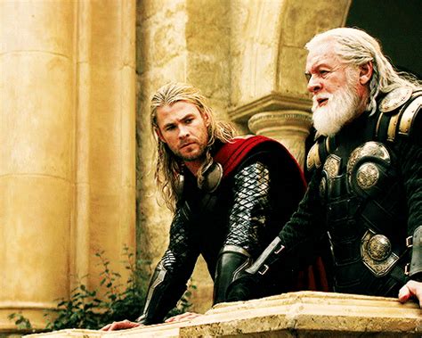 Two Men Dressed As Thor And Loki In Front Of An Old Stone Building With