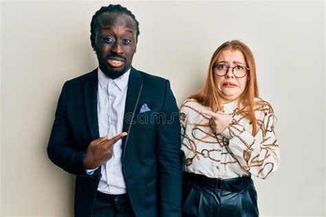 Young Interracial Couple Wearing Business And Elegant Clothes Pointing