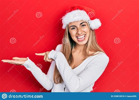 Beautiful Hispanic Woman Wearing Christmas Hat Amazed And Smiling To