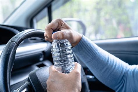 Motorista asiática segurando garrafa para beber água enquanto dirige um