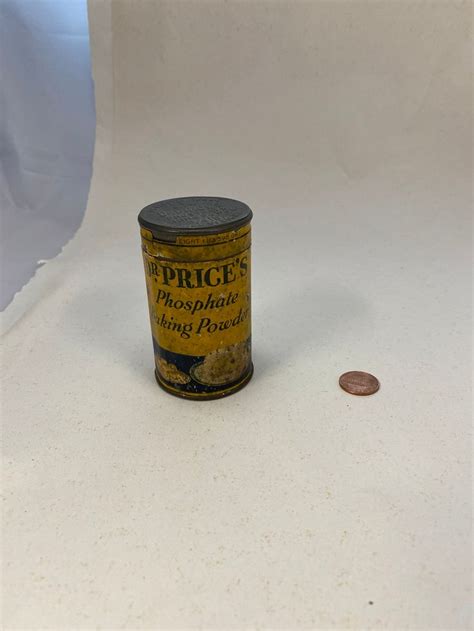 An Old Tin Can Sitting On Top Of A White Table Next To A Penny Coin