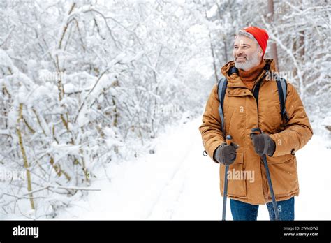 Mature Caucasian Man In Red Hat On A Snowy Background Looking Contented