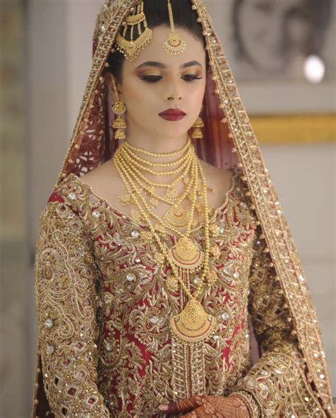 A Woman In A Red And Gold Bridal Outfit With Jewelry On Her Head