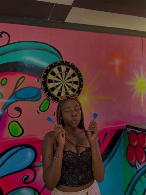 A Woman Standing In Front Of A Colorful Wall With Darts On Her Head And