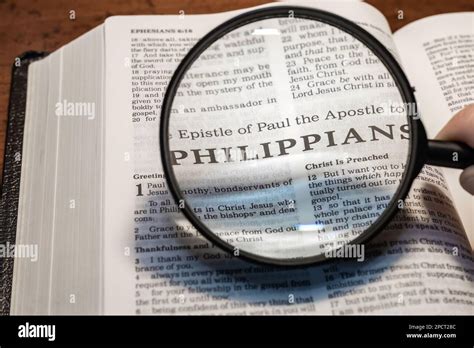 A Closeup Of A Person Holding A Magnifier And Reading The Book Of