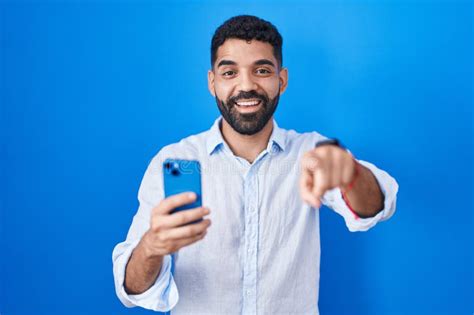 Hispanic Man With Beard Using Smartphone Typing Message Pointing To You