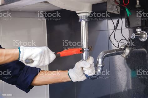 Plumber Fixing White Sink Pipe With Adjustable Wrench Stock Photo