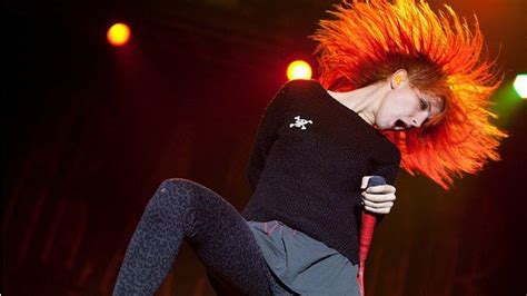 a woman with red hair is on stage holding a microphone and jumping in the air