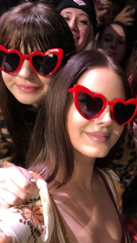 Two Women Wearing Heart Shaped Sunglasses In Front Of A Crowd