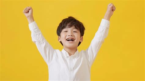 Niño feliz con camisa blanca sonriendo y levantando los brazos mientras