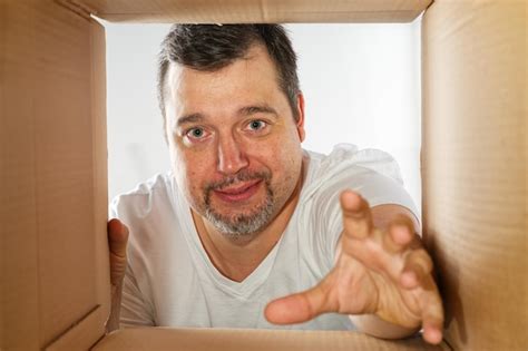 Homem feliz desempacotando abrindo caixa de papelão e olhando para