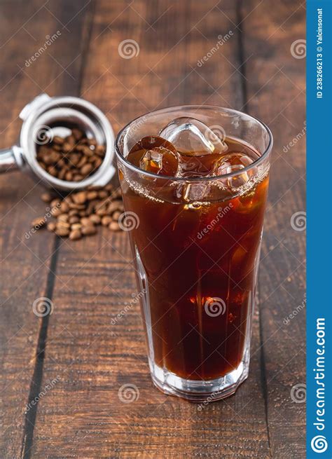 A Cup Of Iced Americano Coffee With Ice Cubes Placed On A Wooden Table