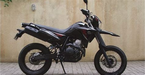 A Black Motorcycle Parked On Top Of A Brick Floor Next To A Wall And Tree