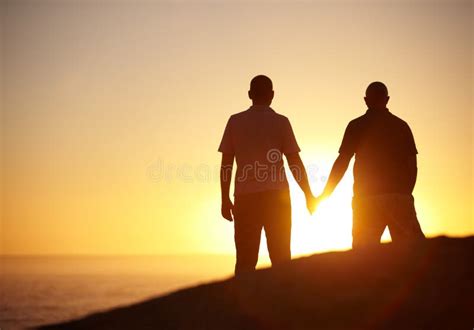 Hes My Sunshine Mature Gay Couple Holding Hands Watching The Sun Set Copyspace Stock Photo
